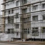 Un bloc de locuințe aflat în proces de reabilitare, cu schele metalice instalate pe întreaga fațadă