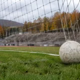 O minge de fotbal lângă poartă pe un stadion în culori de toamnă