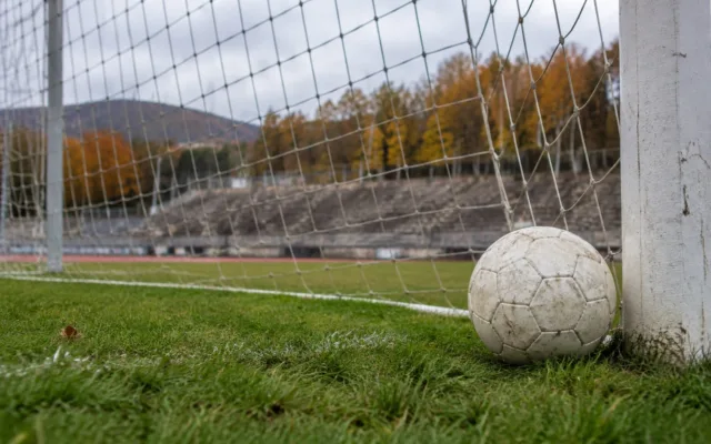 O minge de fotbal lângă poartă pe un stadion în culori de toamnă